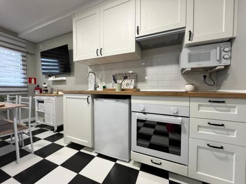a kitchen with white cabinets and a black and white checkered floor at Apartamento Victoria in Potes