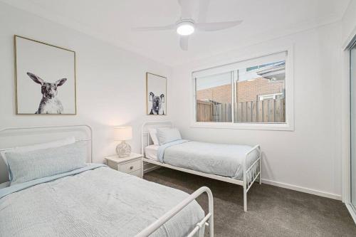ポート・マッコリーにあるA Coastal Hideawayの白いベッドルーム(ベッド2台、窓付)