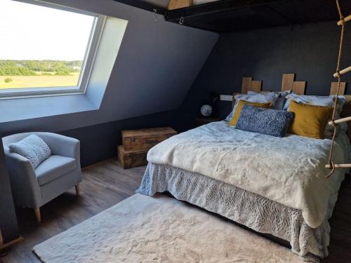 a bedroom with a bed and a chair and a window at Chalet industriel avec filet et spa in Sorigny