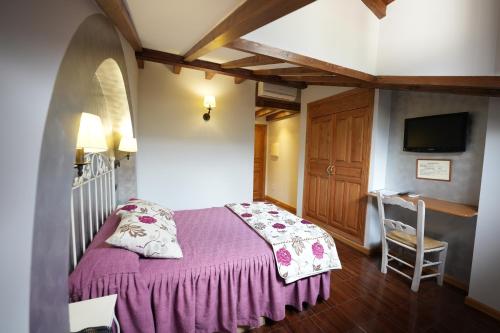 a bedroom with a bed with a purple blanket at Hotel Rural y Restaurante, Rinconcito de Gredos in Cuevas del Valle