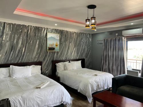 a bedroom with two beds and a couch and a window at The wish executive lodge in Kafue