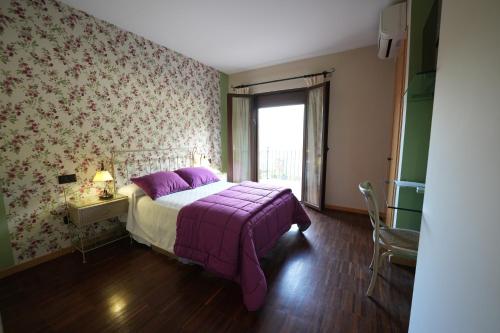 a bedroom with a purple bed and a window at Hotel Rural y Restaurante, Rinconcito de Gredos in Cuevas del Valle