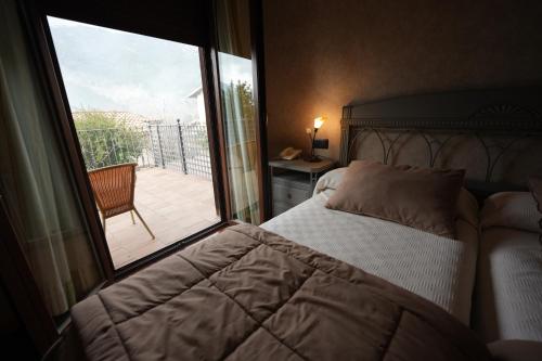 a bedroom with a bed and a window with a balcony at Hotel Rural y Restaurante, Rinconcito de Gredos in Cuevas del Valle