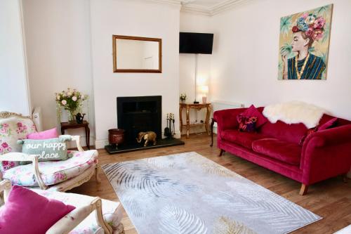 a living room with a red couch and a fireplace at The Pink Door Seaside Holiday Home in Ventnor