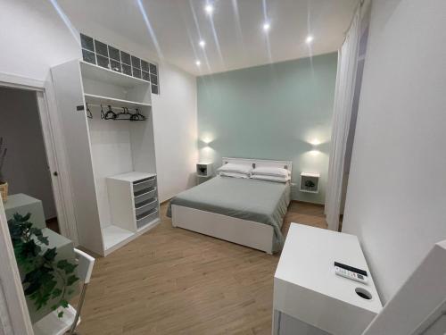 a small white bedroom with a bed and a desk at Casa Maiorino in Torre del Greco