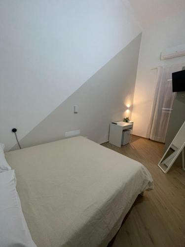 a white bedroom with a bed and a window at Casa Maiorino in Torre del Greco