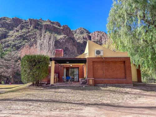 a house with a mountain in the background at Cabañas Del Sol in Valle Grande
