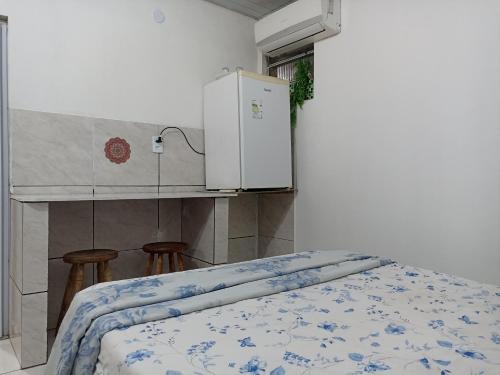a room with a bed with a refrigerator and two stools at Refúgio de Piratininga 104 in Niterói