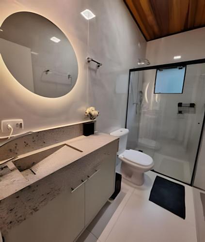 a bathroom with a sink and a toilet and a mirror at Chalé Verbena - Recanto Veky in Campos do Jordão