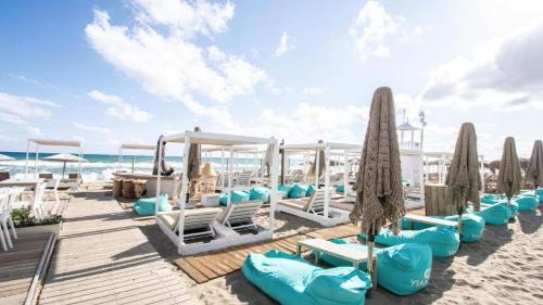 a row of lounge chairs and umbrellas on the beach at Apartment Simply 205 in Gázion