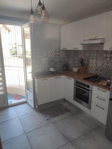 une cuisine avec des armoires blanches et une cuisinière dans l'établissement Appartement avec parking privée, à Avignon