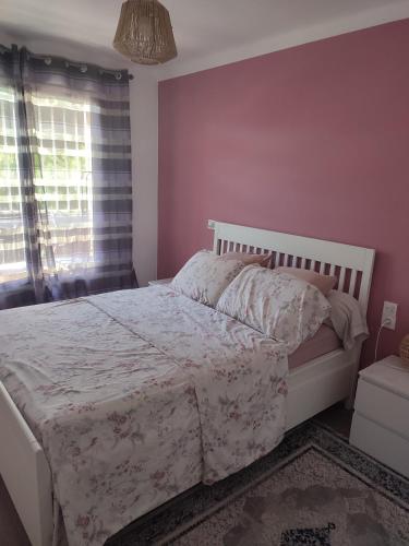 - une chambre avec un lit blanc et un mur rose dans l'établissement Appartement avec parking privée, à Avignon