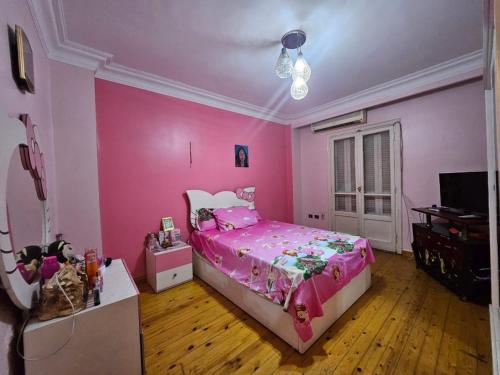 a pink bedroom with a bed and a television at Villa Apartment Nile View in City Center in Cairo