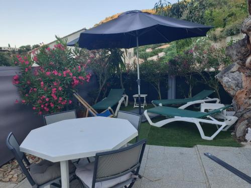 a patio with a table and chairs and an umbrella at Les Restanques du Sud in Le Lavandou