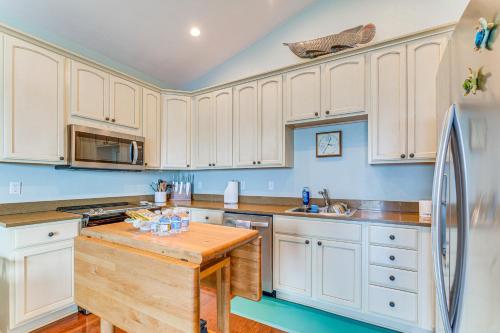 a kitchen with white cabinets and a refrigerator at Steps to Beach Waterfront Cedar Key Home! in Cedar Key