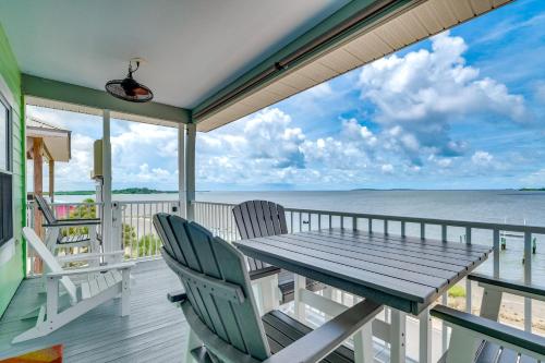 a porch with a wooden table and chairs and the ocean at Steps to Beach Waterfront Cedar Key Home! in Cedar Key