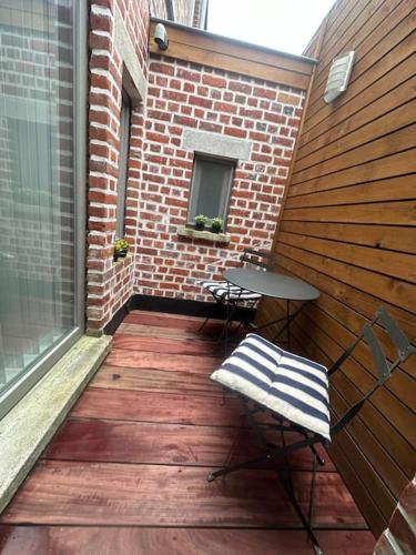a patio with a table and chairs and a building at Woning Meningate in Ypres
