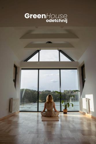 a woman sitting on a floor in a room with a large window at Green House - nad jeziorem z pomostem in Olsztyn