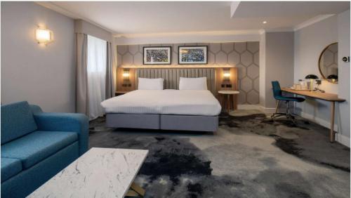 a hotel room with a bed and a blue couch at London Chigwell Prince Regent Hotel, BW Signature Collection in London