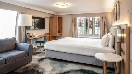 a bedroom with a bed and a couch and a desk at London Chigwell Prince Regent Hotel, BW Signature Collection in London