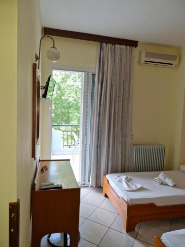 a hotel room with two beds and a window at Hotel Athina in Asprovalta