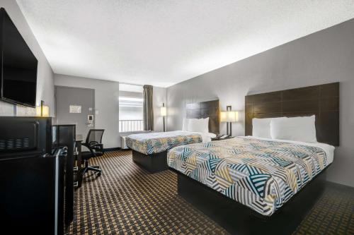 a hotel room with two beds and a flat screen tv at Motel 6 Chickasha, OK in Chickasha
