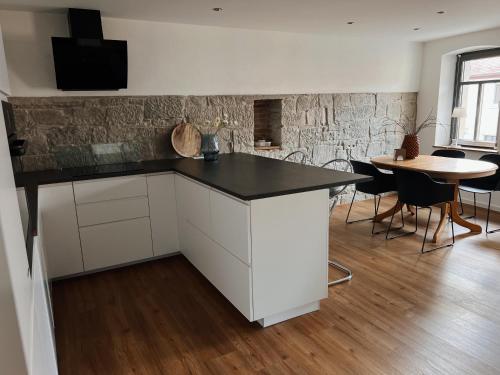 a kitchen with white cabinets and a black counter top at Ferienwohnung am Rathaus in Wiesenbronn