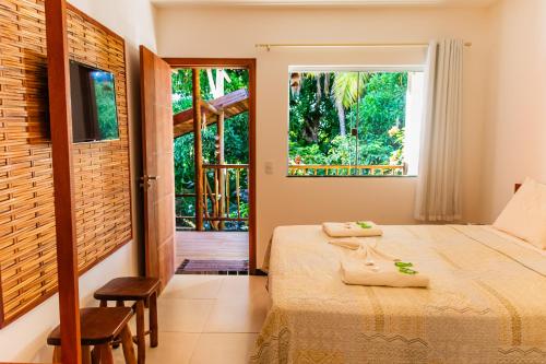 a bedroom with a bed and a large window at Morena Jambo in Arraial d'Ajuda