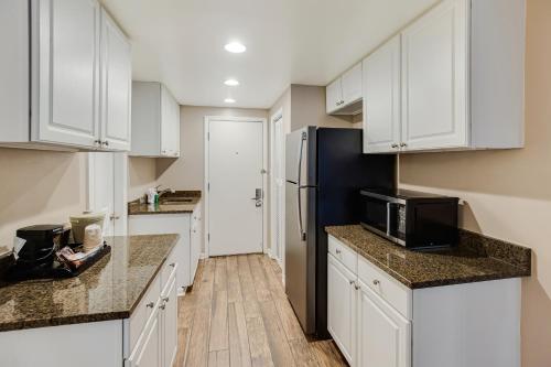 a kitchen with white cabinets and a black refrigerator at Oceanfront Litchfield Inn in Pawleys Island