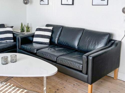 a black leather couch in a living room with a white table at 8 person holiday home in Bagenkop-By Traum in Bagenkop