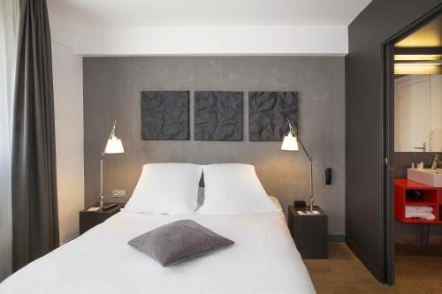 a bedroom with a large white bed with two pillows at Hotel Litteraire Alexandre Vialatte, BW Signature Collection in Clermont-Ferrand