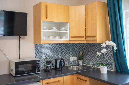 a kitchen with a sink and a microwave at MeDoRa Park - Hotel MeDoRa*** in Gárdony