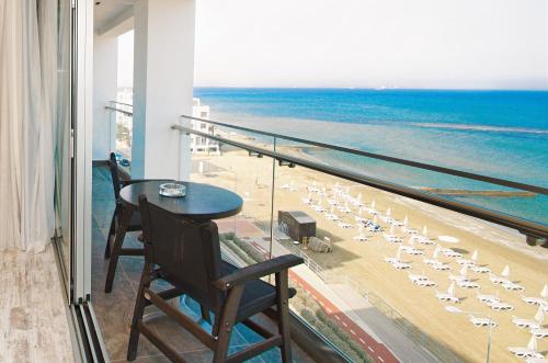 a balcony with a table and chairs and the beach at The Ciao Stelio Deluxe Boutique Hotel - Adults Only in Larnaka
