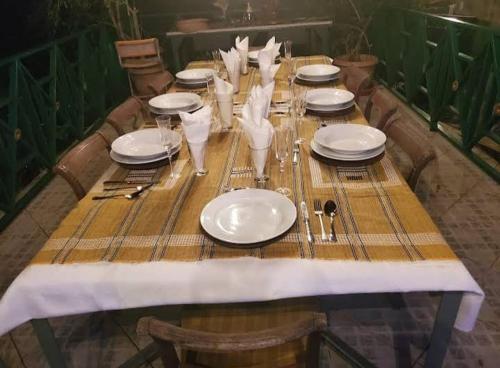 a wooden table with white plates and glasses on it at Hillcrest Sanctuary in Maraval