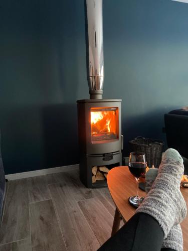a living room with a stove with a glass of wine at Captain's Rest with Hot Tub and Sauna in Dunvegan