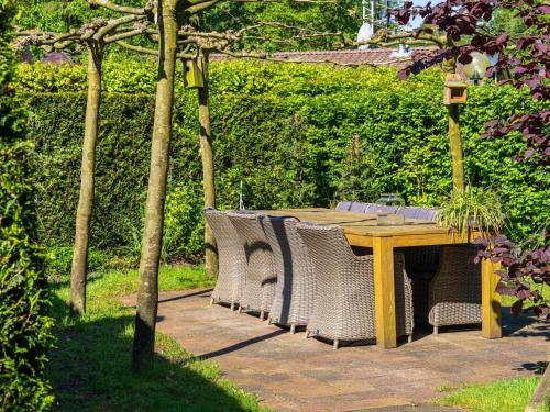 a wooden table with chairs around it in a garden at De 5 Platanen in Hulshorst