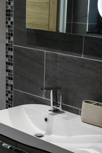 a white sink in a bathroom with a mirror at Captain's Rest with Hot Tub and Sauna in Dunvegan