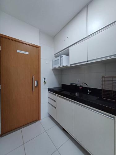 a kitchen with white cabinets and a wooden door at Flat térreo e condomínio aconchegante ! in Ipojuca