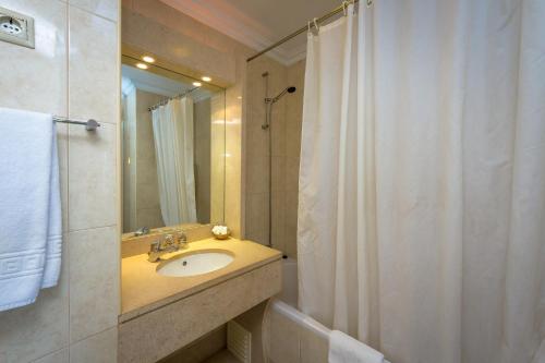 a bathroom with a sink and a shower with a mirror at Hotel Atismar in Quarteira