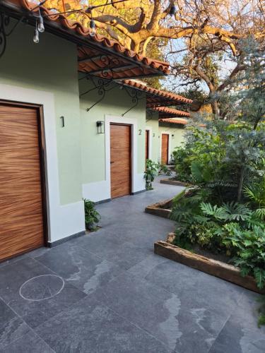 a walkway leading to a house with two garage doors at Hotel Boutique Villa Escondida, A Pasos de Lo Mejor en Tlaquepaque in Guadalajara