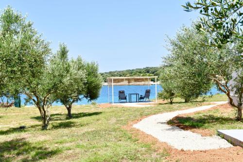 a house by the water with trees and a gazebo at Seaside holiday house Cove Krlic, Pag - 23435 in Novalja