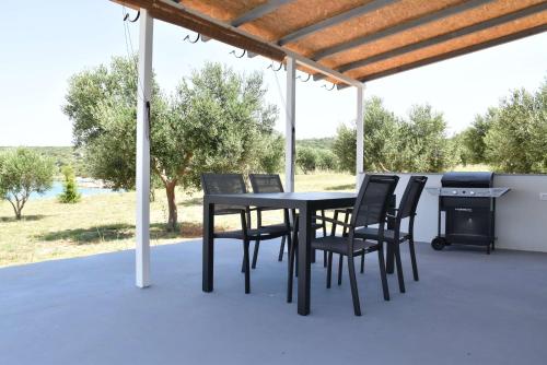 a black table and chairs on a patio with a grill at Seaside holiday house Cove Krlic, Pag - 23435 in Novalja