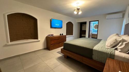 a bedroom with a bed and a tv on the wall at Hotel Boutique Villa Escondida, A Pasos de Lo Mejor en Tlaquepaque in Guadalajara