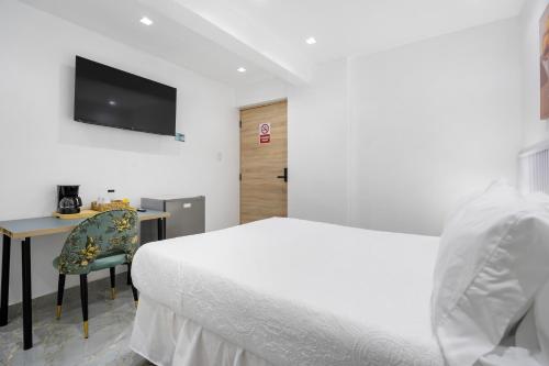 a bedroom with a bed and a desk and a television at Hotel Vista Caribe Azúa in Azua de Compostela