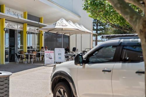 a white suv parked in front of a restaurant at Seaside Beach House, luxury 3x2, fire pit, secure garden, pet friendly, sleeps 8, opp cafe in Mandurah