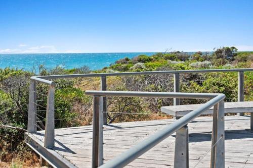 a wooden boardwalk with a bench on the beach at Seaside Beach House, luxury 3x2, fire pit, secure garden, pet friendly, sleeps 8, opp cafe in Mandurah