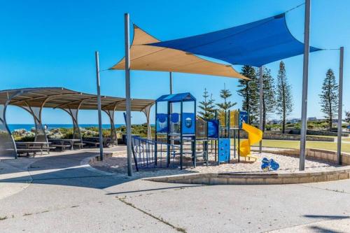 a park with a playground with blue and yellow equipment at Seaside Beach House, luxury 3x2, fire pit, secure garden, pet friendly, sleeps 8, opp cafe in Mandurah