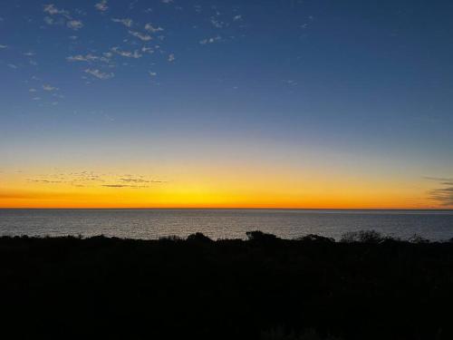 a sunset over a body of water with the sky at Seaside Beach House, luxury 3x2, fire pit, secure garden, pet friendly, sleeps 8, opp cafe in Mandurah