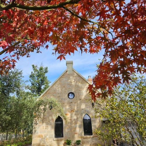an old stone church with a clock on it at The Old School Historic Stay for 2 Adelaide Hills in Balhannah