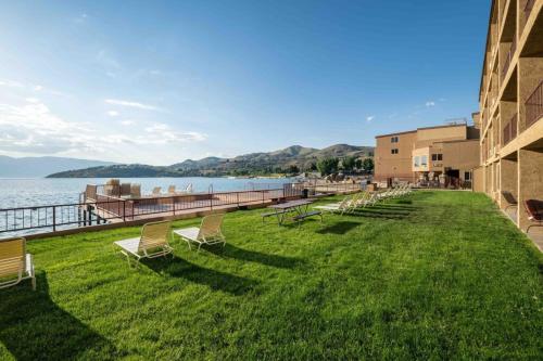 a row of chairs sitting on the grass near the water at Lake Chelan Executive Condo in Chelan
